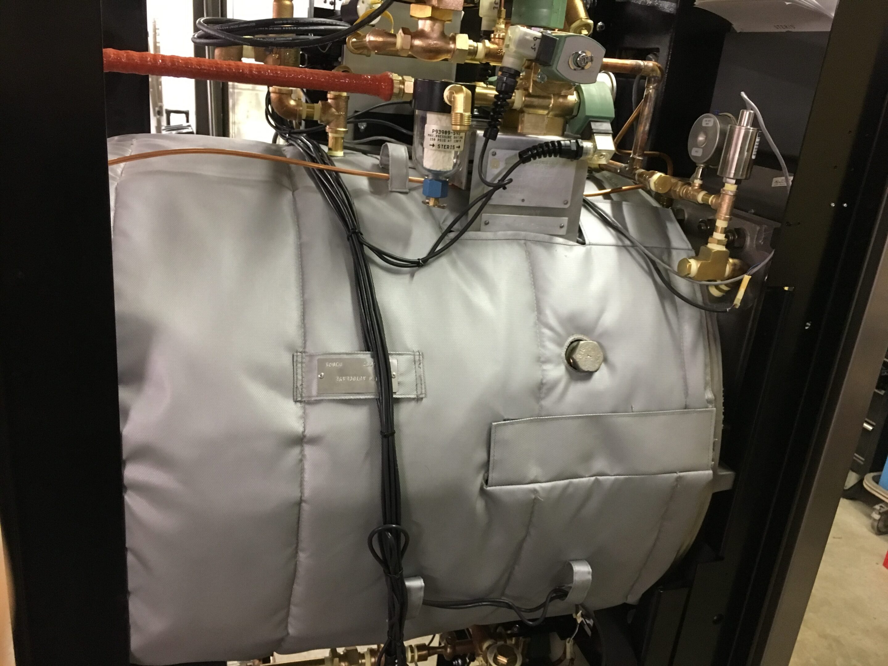 Insulated industrial equipment with pipes and gauges.